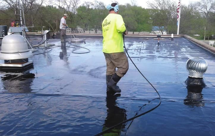 A-1 crew member power washing the oxidized EPDM roof with Gaco Wash before restoration
