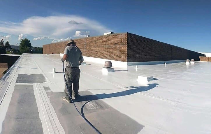 A-1 crew spray-applying Gaco S20 100% silicone topcoat over the restored Colome Elementary School roof