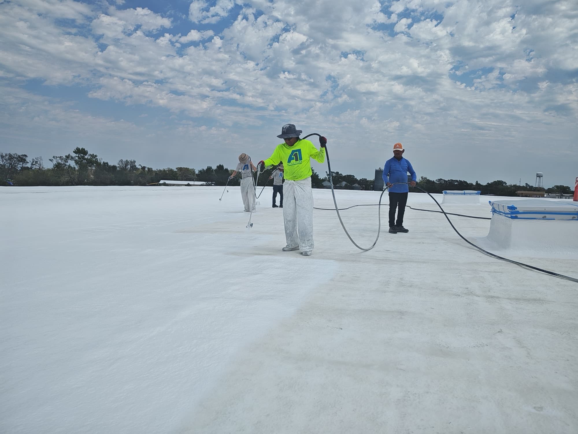 A-1 crew spray-applying white Gaco S20 silicone coating on the Woonsocket school spray foam roof