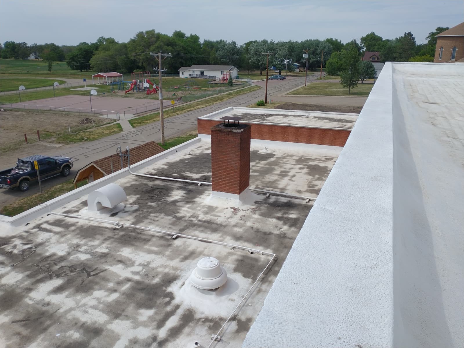 Parapet-level view of the failing patched spray foam roof on the Woonsocket school before restoration